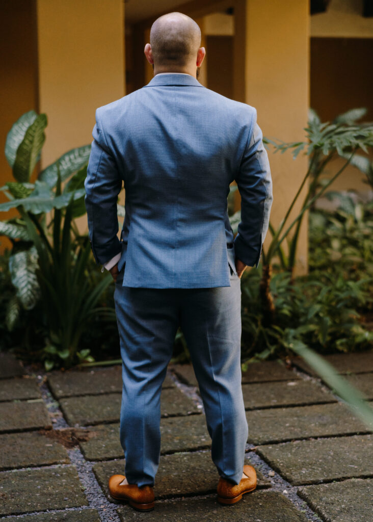 man in custom Roma Tailor wedding suit, facing away from the camera with hands in his pockets