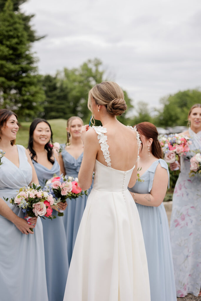 bride is facing her bridesmaids who are all wearing blue dresses and holding pink bouquets shot by the timeless wedding photographer Monika Eisenbart