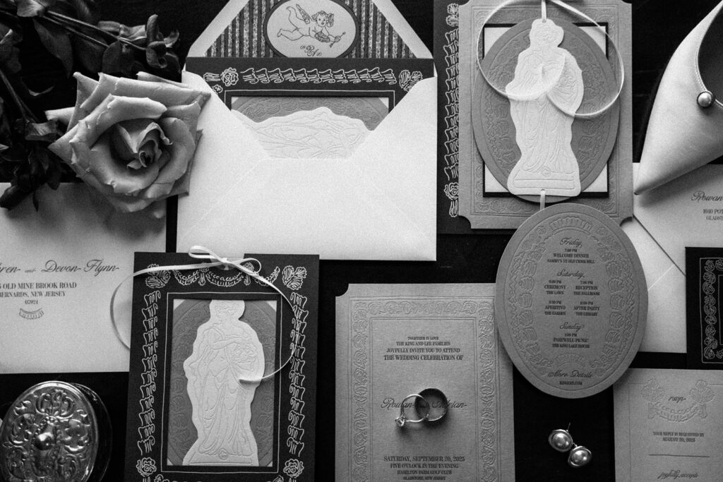 black and white image of stationery, wedding rings and earrings