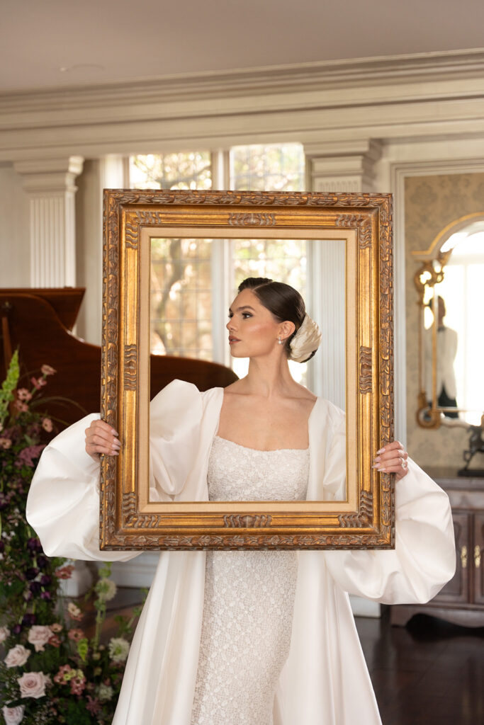 soft glam bridal makeup, while bride holds a picture frame around her face